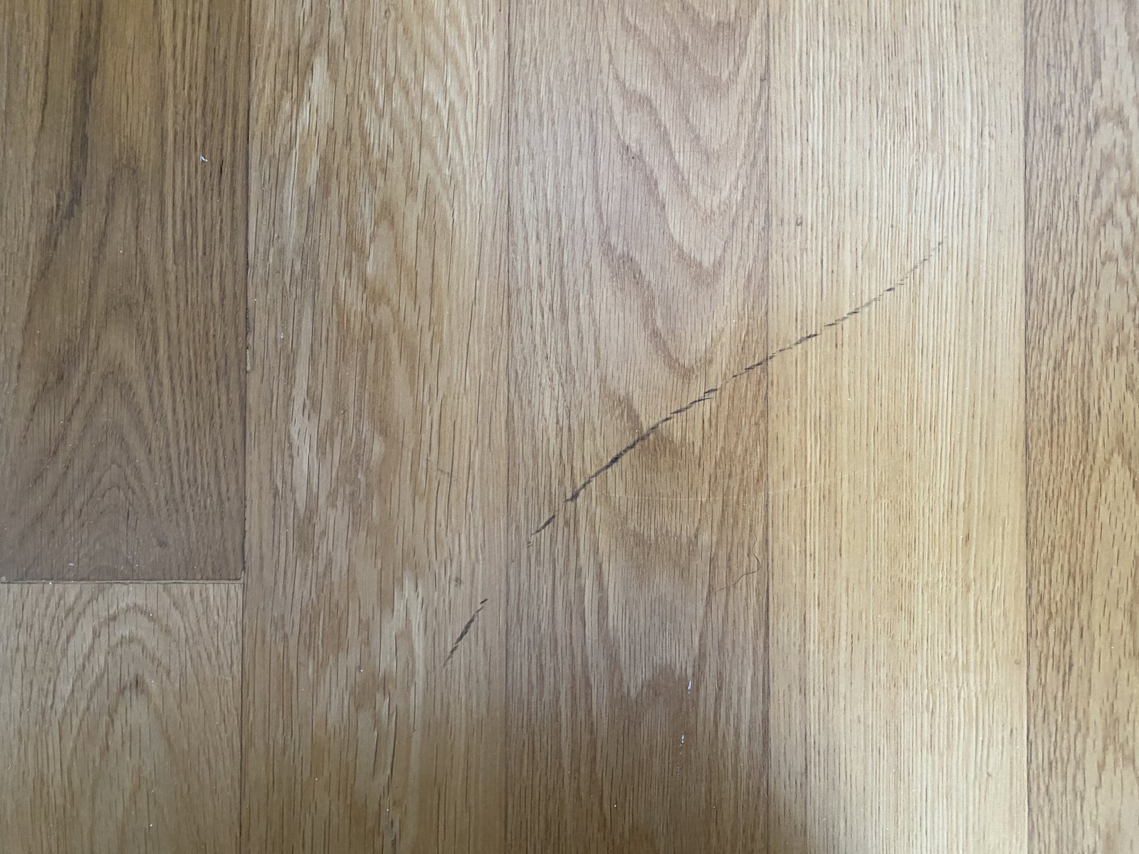 Deep X-shaped scratches in wooden flooring documented at move-in inspection